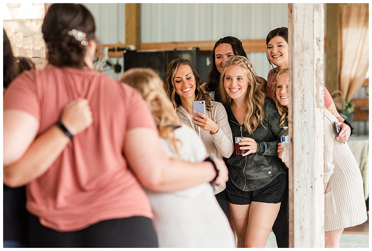 a group of girls smiling at a mirror, getting ready for a country reflections wedding in sparta