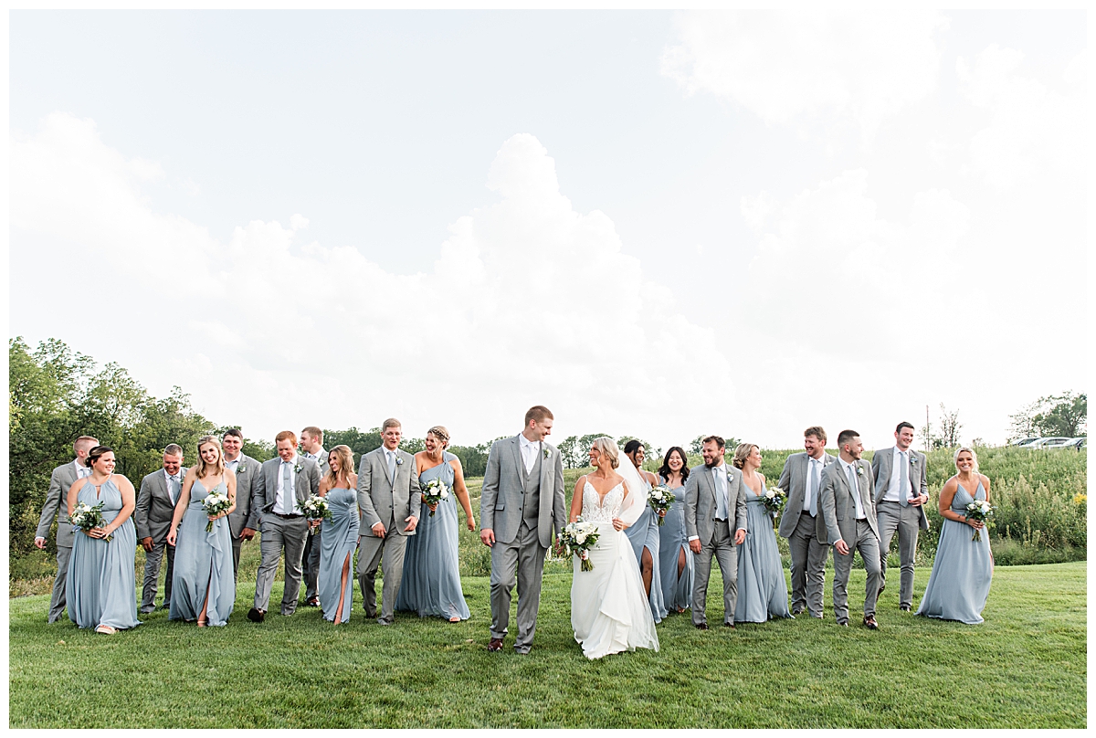 wedding party walking through a field at a modern barn venue outside of madison, wisconsin