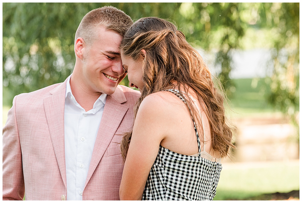 couple snuggling, laughing at each other during engagement photos at doty park in neenah