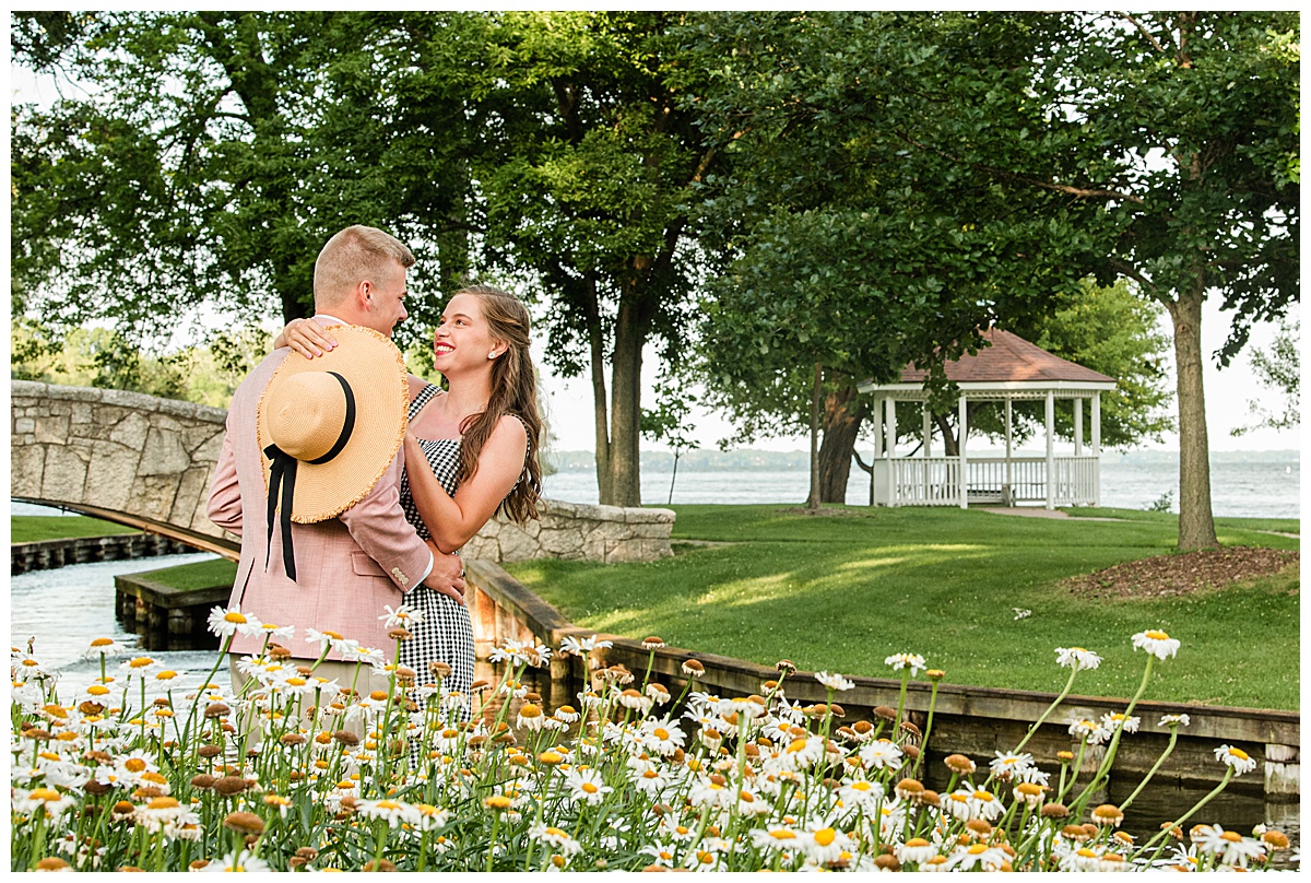 cute couple standing by flowers at doty park in neenah by wedding photographer morgan madeleine photography