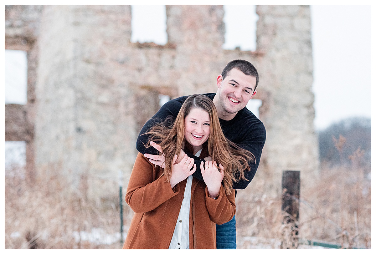 a couple smiling in front of the farmstead ruins by indian lake county park