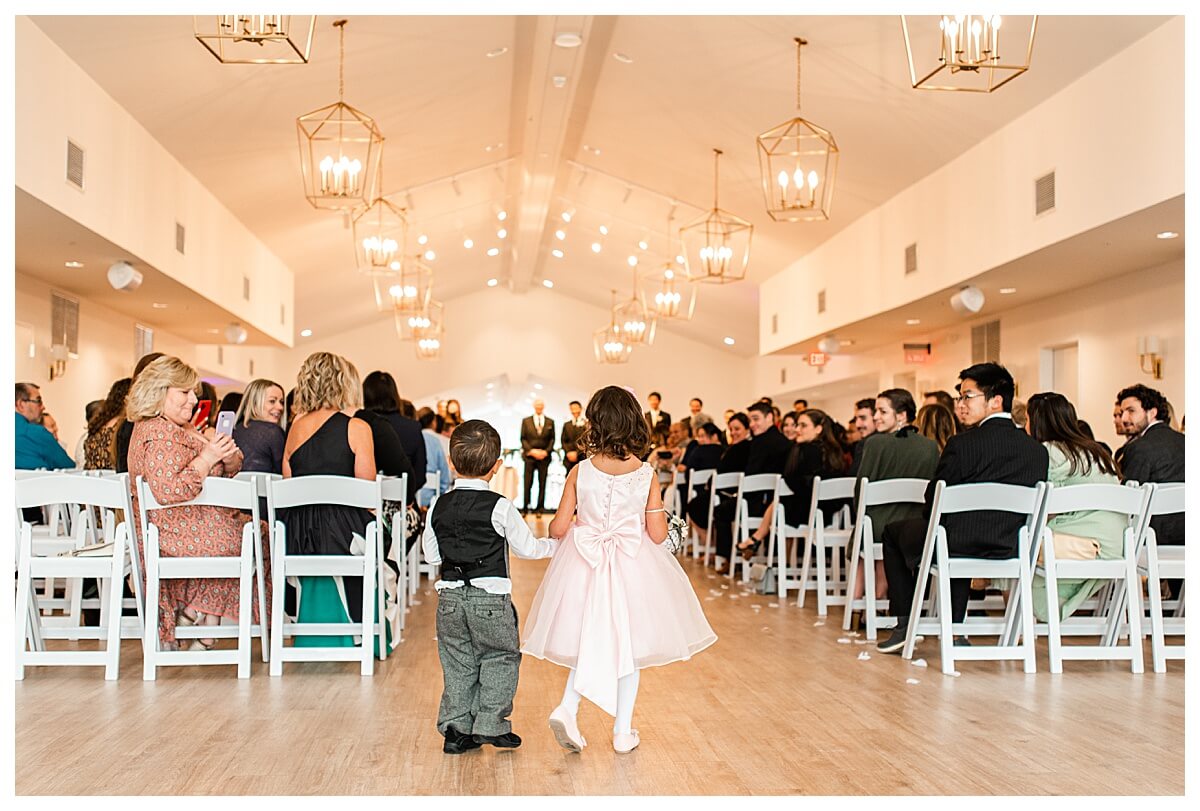 flower girl and ring bearer walking down the aisle at an indoor ceremony venue in wisconsin