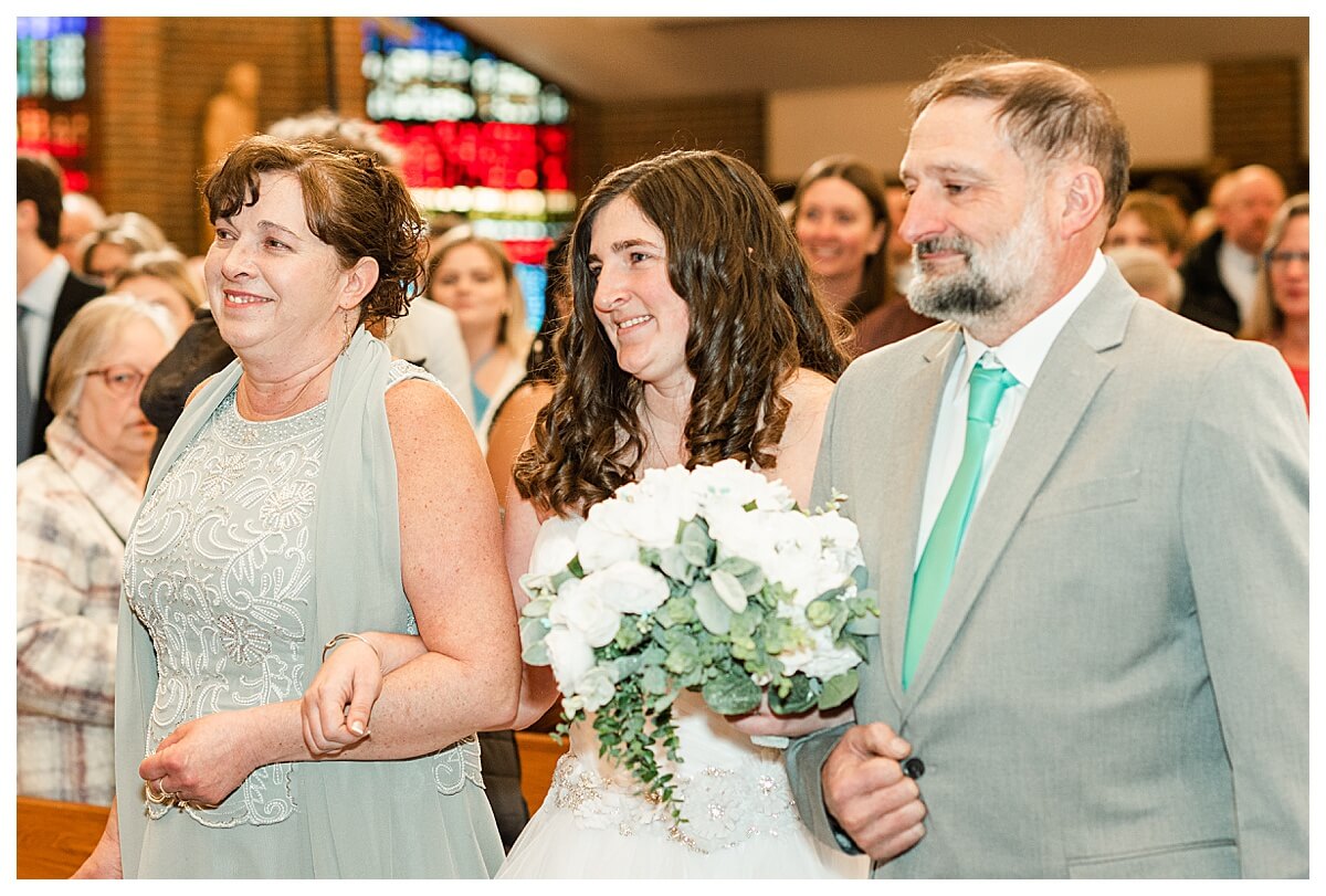 bride walks down the aisle with dad and mom at a church wedding in wisconsin