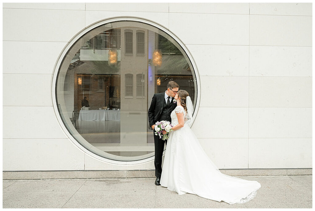 A bride and groom outside of the circle window at the Overture Center in Madison, WI