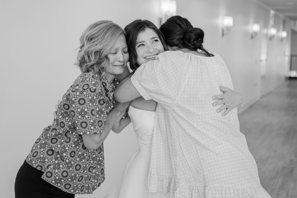 A mom and sister hugging a bride before her wedding day