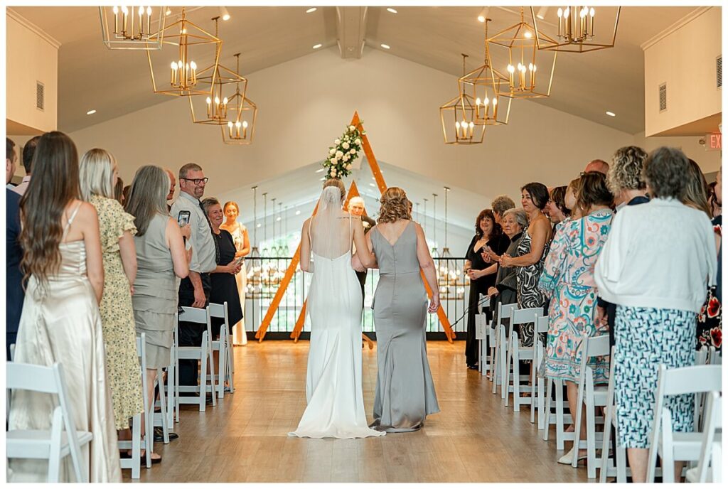 Bride and mom walking down the aisle inside The Eloise Wedding Venue Mt Horeb